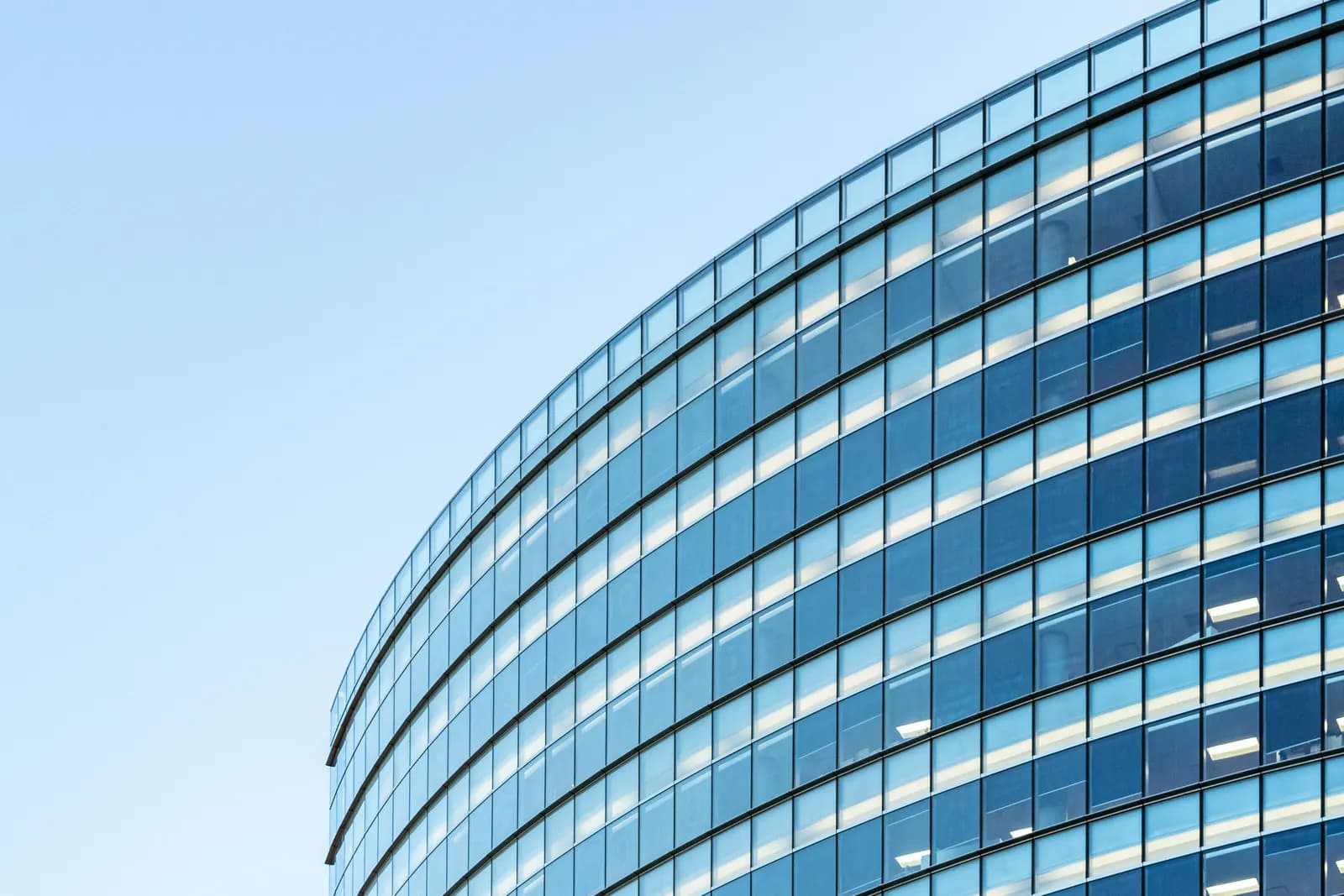 A modern multi-storey glass office building against a clear sky